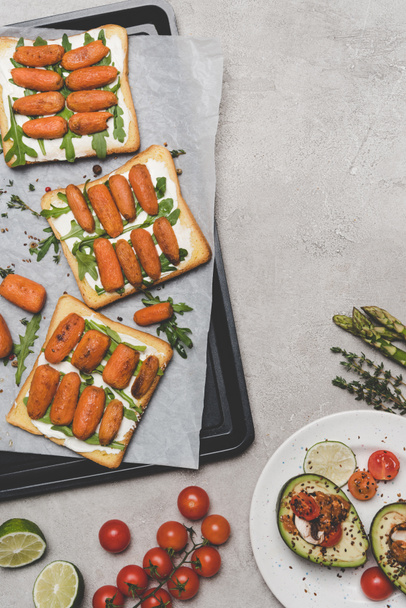 top view of healthy sandwiches with baby carrots and arugula on grey - Fotoğraf, Görsel