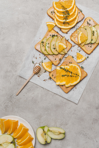 top view of healthy sandwiches with fresh fruits and honey on grey  - 写真・画像
