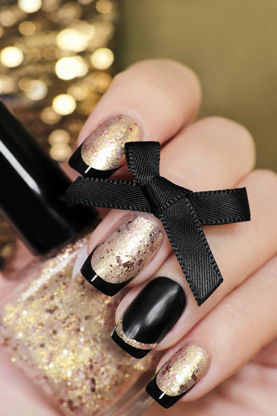 Black and gold French manicure with nail Polish in hand closeup. - Foto, immagini