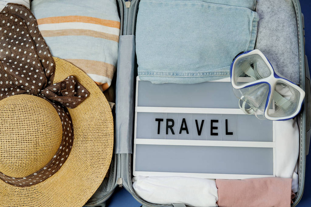 Travel board in Open suitcase packed with clothes. Summer vacati - Фото, изображение