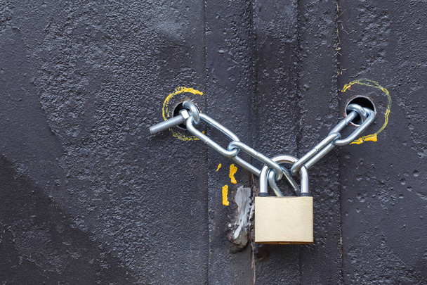 Padlock with chain on the iron gate. Black background. The concept protects reliably. - Фото, изображение