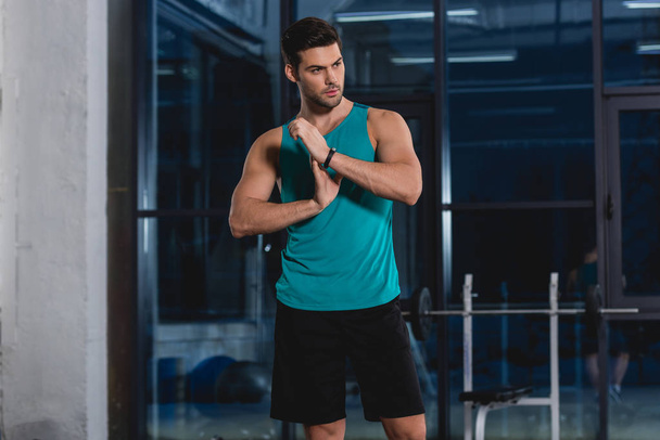 handsome sportsman stretching arms in gym - Zdjęcie, obraz
