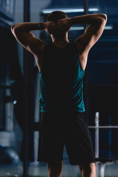 back view of silhouette of muscular sportsman in gym - Foto, imagen