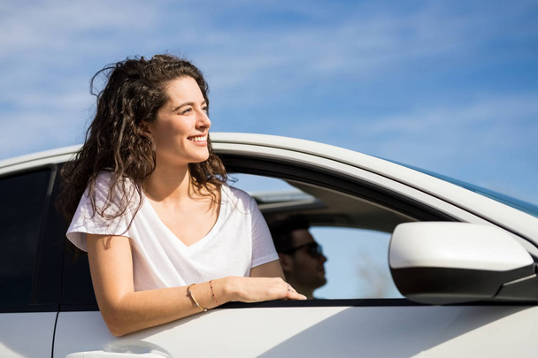 Portrait of young woman looking on road with her head out of car window - Photo, Image