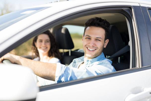 joven hombre conduciendo coche con novia en el asiento del pasajero
  - Foto, Imagen