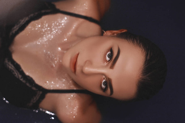 girl in the bathtub with blue water. girl in lingerie with wet hair. portrait of a woman with big eyes. - Foto, immagini