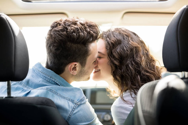 młody mężczyzna całuje dziewczynę na siedzeniu pasażera  - Zdjęcie, obraz
