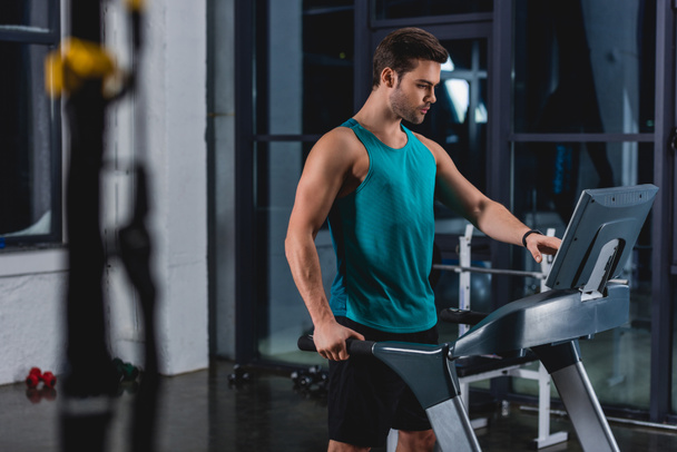 handsome sportsman training on treadmill in gym - Фото, зображення