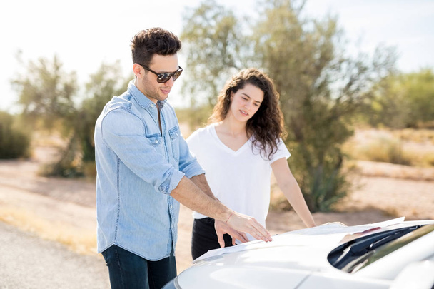 Man and woman standing near car outdoors and trying find right way  - Foto, Imagem