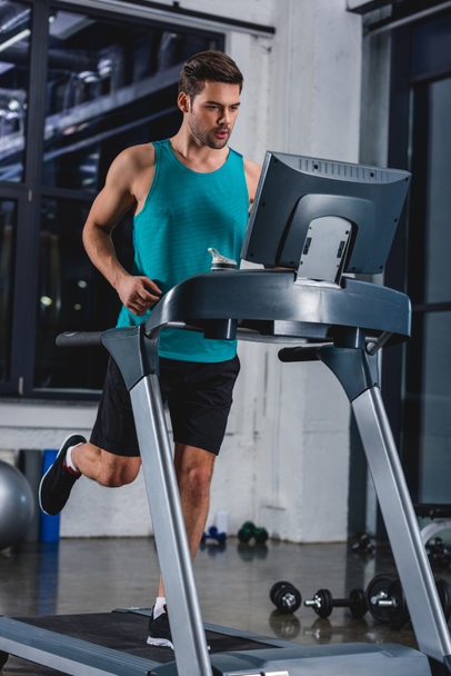 athletic man running on treadmill in sports center - 写真・画像