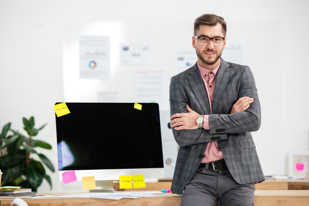 ritratto di uomo d'affari in giacca e cravatta e occhiali in piedi sul posto di lavoro con schermo del computer vuoto in ufficio
 - Foto, immagini