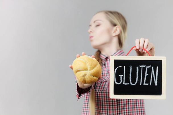 Woman holding board with gluten sign and bun bread - Фото, зображення