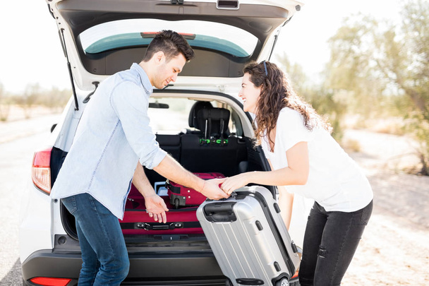 Jovem e mulher carregando suas malas no porta-malas do carro
  - Foto, Imagem