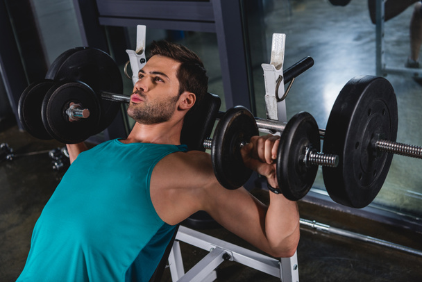 muscular sporty man exercising with dumbbells in gym - Foto, imagen
