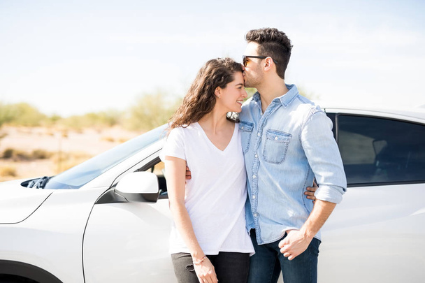Nuori mies suudella otsa tyttöystävä kun seisoo lähellä autoa
 - Valokuva, kuva