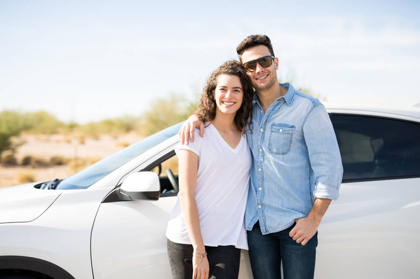 jovem casal de pé juntos perto de carro e sorrindo
  - Foto, Imagem