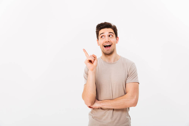 Positive brunette man 30s wearing beige t-shirt gesturing finger - Photo, Image