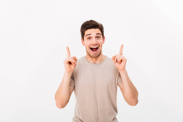 Surprised brunette man 30s wearing beige t-shirt gesturing finge - Fotografie, Obrázek