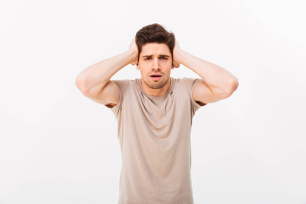 Photo of muscular adult man 30s grabbing his head or covering ea - Foto, Imagen
