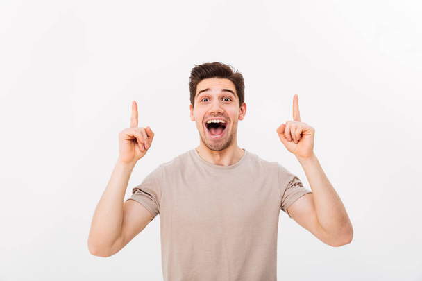 Image of optimistic man in casual t-shirt smiling and pointing f - Photo, image