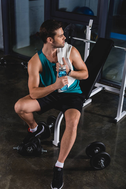 Müder Sportler ruht mit Handtuch und Sportflasche im Fitnessstudio - Foto, Bild
