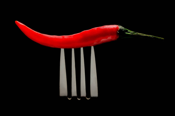 chili pepper on fork on black background - Foto, Imagen