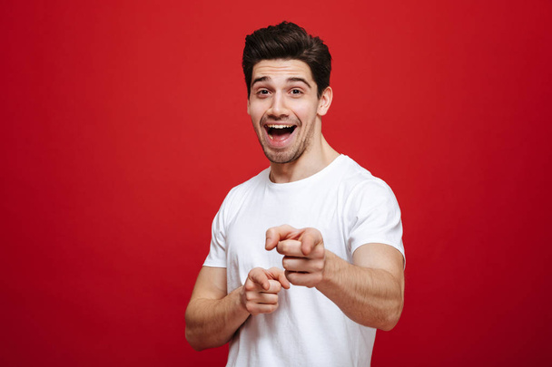 Portret młodego mężczyzny uśmiechający się w biały t-shirt palcem wskazującym - Zdjęcie, obraz