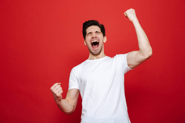 Portrait of a cheerful young man in white t-shirt celebrating - Фото, зображення