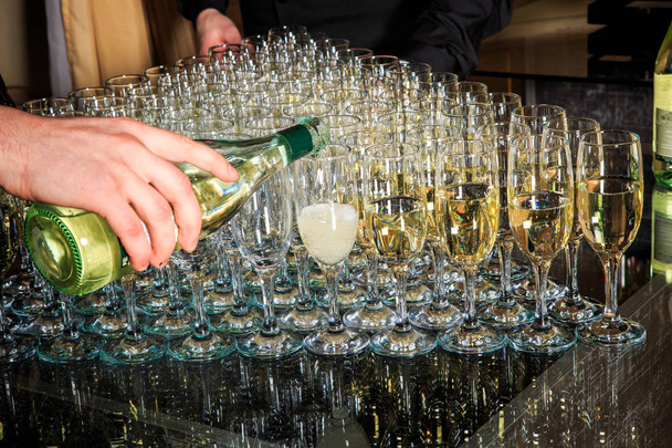 set di bicchieri di champagne parzialmente riempiti disposti a triangolo su sfondo specchio sul servizio di catering banchetto
 - Foto, immagini
