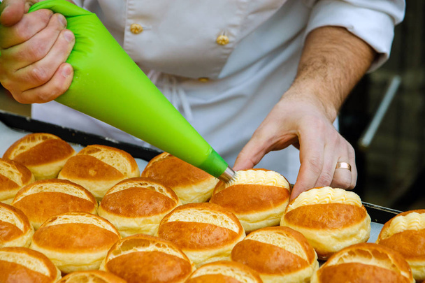 the pastry chef prepares the rolls and lubricate them with cream - Foto, Imagem
