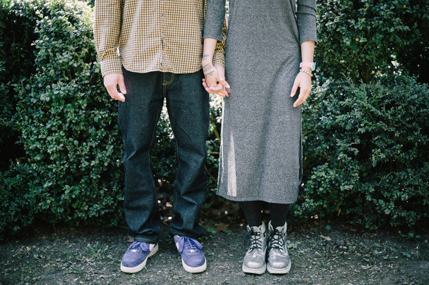 Lowe section of couple holding hands at park lawn - Fotó, kép