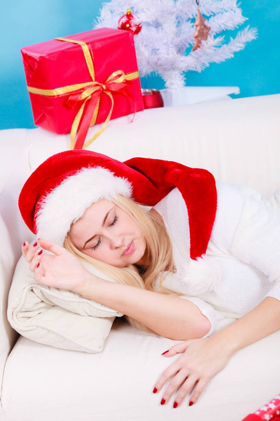 girl wearing santa hat sleeping on sofa at home - Foto, Imagen