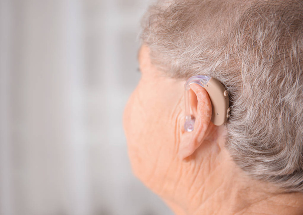 Старша жінка з слуховим апаратом у приміщенні
 - Фото, зображення