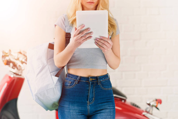 обрезанный снимок молодой студентки с помощью планшета перед винтажным скутером
 - Фото, изображение