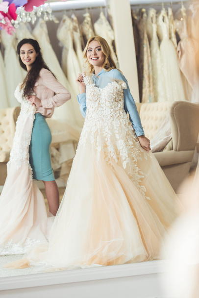  Brides holding lace dresses in wedding salon - Photo, Image