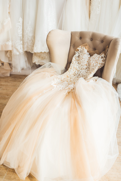 Lace wedding dress on chair in wedding salon - Фото, зображення