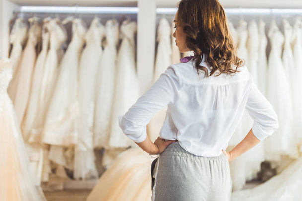 Attractive woman looking at dresses in wedding fashion shop - Fotoğraf, Görsel