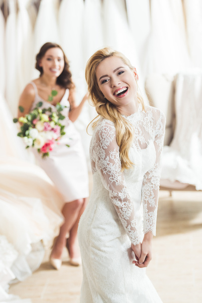 Uśmiechający się kobiet w ślubne suknie z kwiatami w salonie ślubu - Zdjęcie, obraz