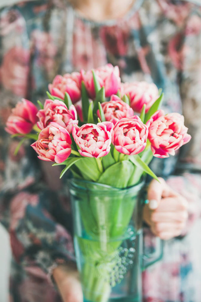 Spring flowers arrangement. Woman in colorful silk dress holding bouquet of fresh pink tulips - Photo, image