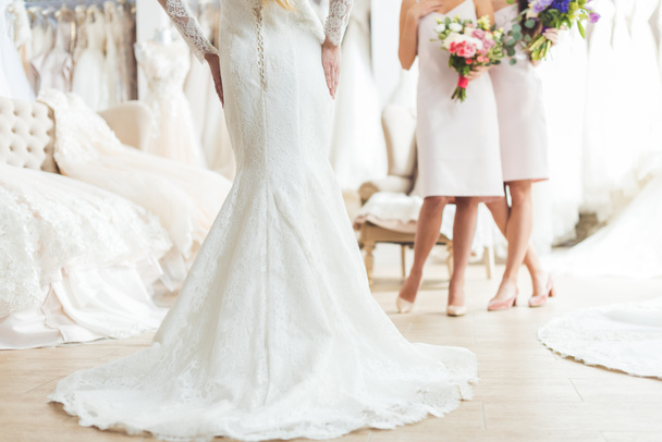 Cropped view of bride and bridesmaids with flowers in wedding salon - Fotoğraf, Görsel