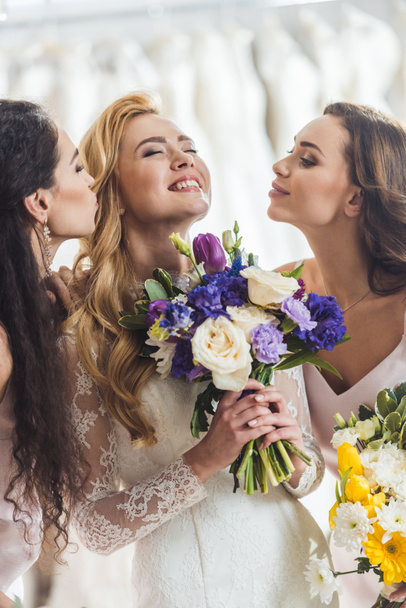 Happy women in wedding dresses with flowers in wedding atelier - Photo, image