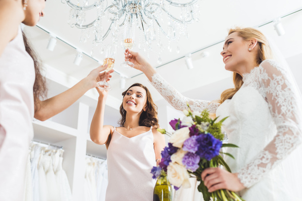 Mujeres sonrientes en vestidos de novia tostadas con champán en el salón de bodas
 - Foto, imagen
