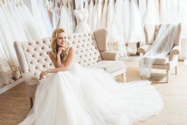 Giovane sposa in abito di tulle seduta sul divano nel salone di nozze
 - Foto, immagini
