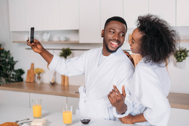 キッチンで selfie を取って笑顔のアフリカ系アメリカ人カップル - 写真・画像
