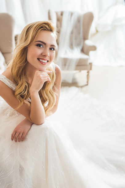 Smiling bride wearing tulle dress in wedding atelier - 写真・画像