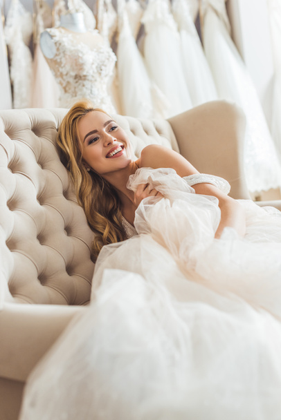 Attractive bride resting on sofa in wedding salon - Photo, Image