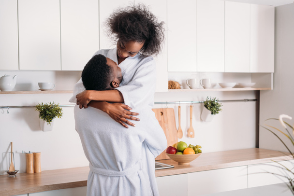 Jeune homme afro-américain élever petite amie souriante dans la cuisine
 - Photo, image