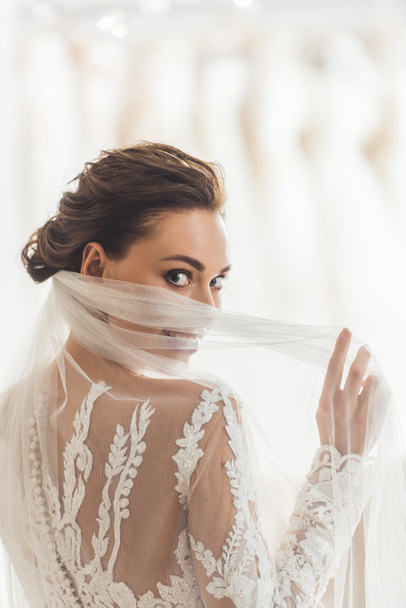 Beautiful tender bride wearing dress in wedding atelier - Photo, image
