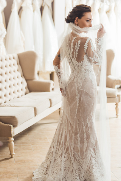 Attractive woman wearing wedding dress in wedding fashion shop - Фото, изображение
