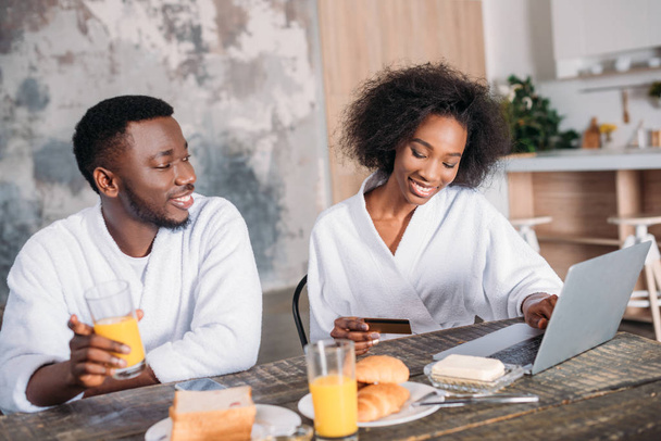 African american couple having breakfast and doing online shopping in kitchen - Фото, зображення